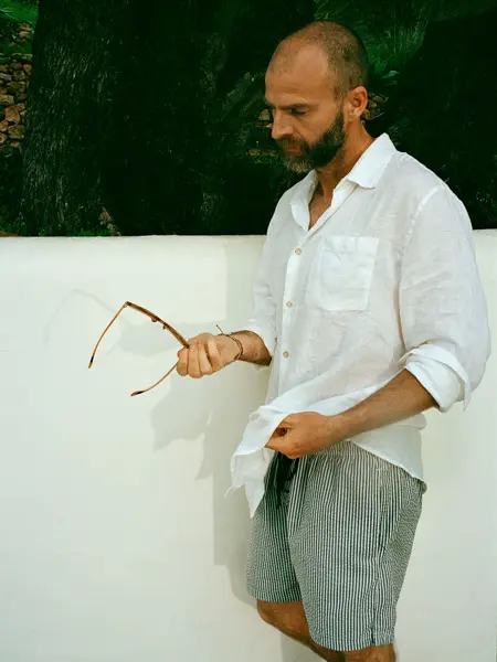 Mann i hvit linskjorte og stripete badebukse.