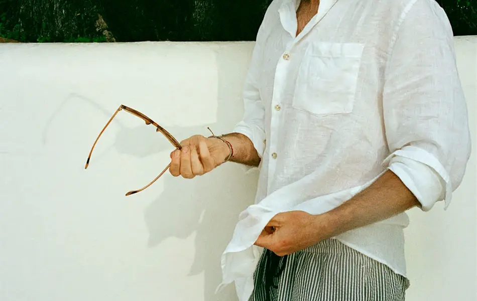 Mann i hvit linskjorte og stripete badebukse.