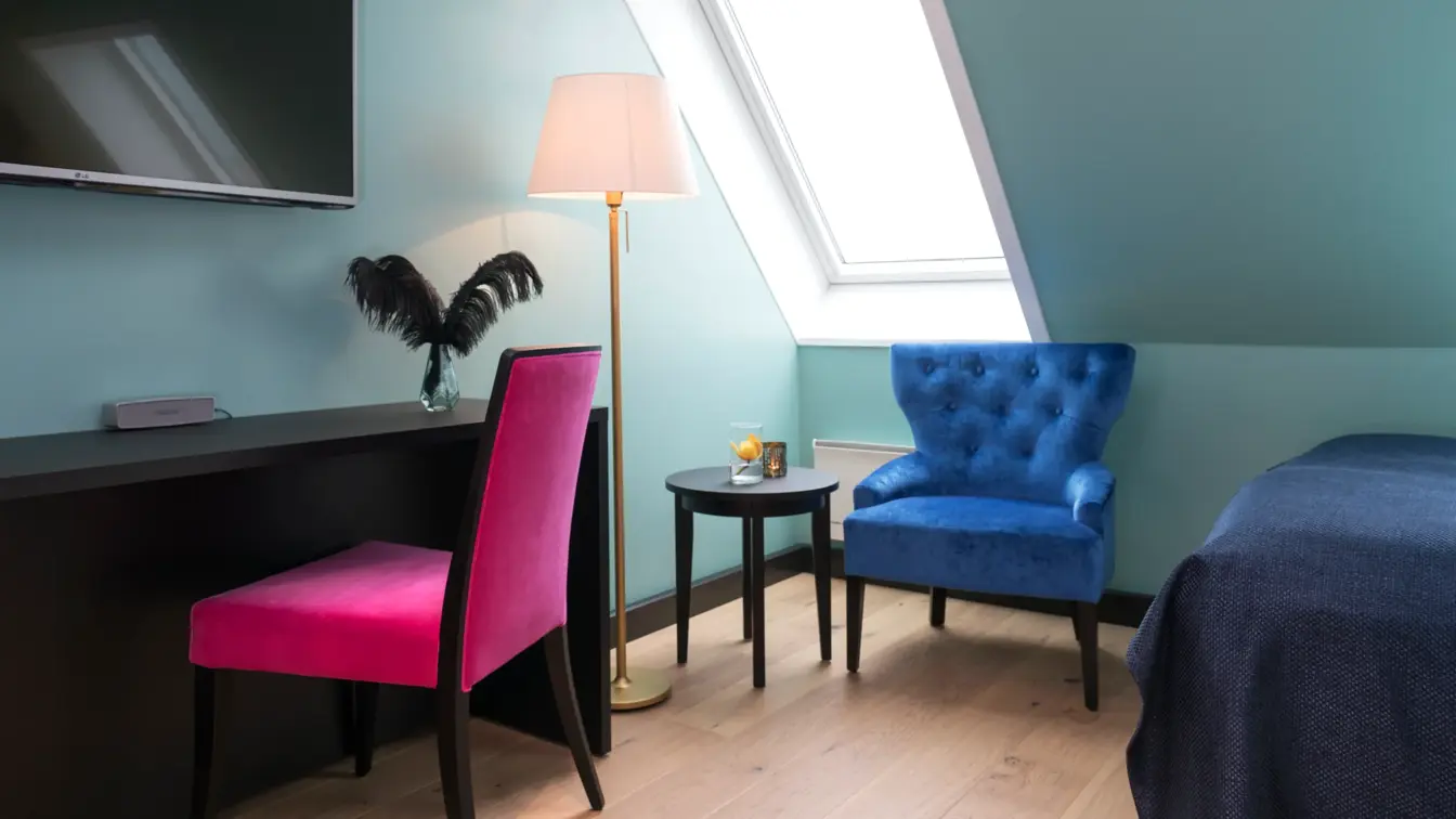 TV, skrivepult skrått tak med vindu og stol på suite på Thon hotel Terminus i Oslo sentrum nær Jernbanetorget
