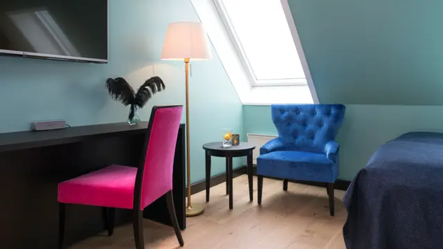 TV, skrivepult skrått tak med vindu og stol på suite på Thon hotel Terminus i Oslo sentrum nær Jernbanetorget