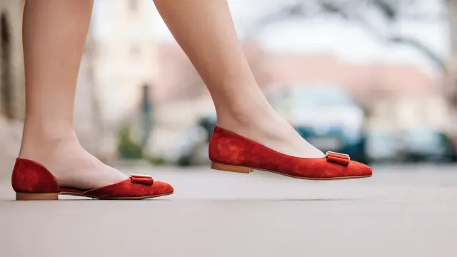 dame med røde ballerinasko som går på en gate