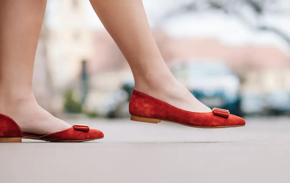 dame med røde ballerinasko som går på en gate