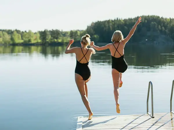 To damer i svart bikini hopper fra brygga 