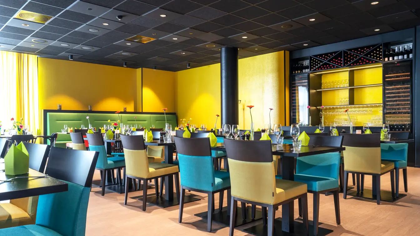 Dekkede bord med gule vegger og grønn sofa i restauranten på Thon Hotel Alta