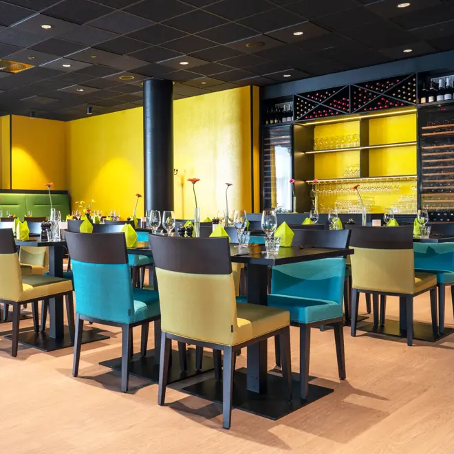 Dekkede bord med gule vegger og grønn sofa i restauranten på Thon Hotel Alta