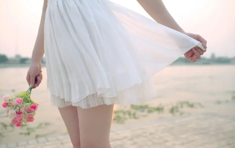 Nærbilde av tyllskjørt på jente som holder rosa blomster i hånden 