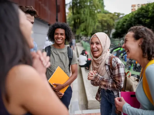 Multi-ethnic group of college students looking very happy talking at the school and laughing