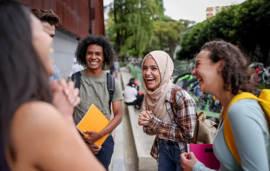 Multi-ethnic group of college students looking very happy talking at the school and laughing