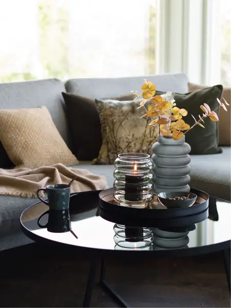 Sofa med bord dekket med vase med en kvist