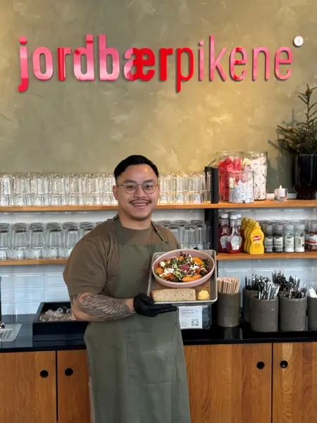 Mann hoiilder frem salat hos jordbærpikene