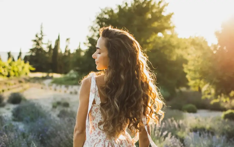 Dame med brunt hår og hvit langt blomstrete kjole i skogen
