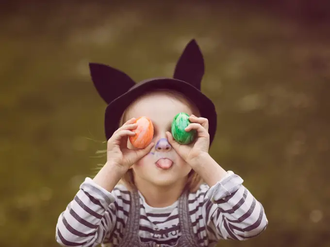 Jente som holder to påskeegg foran øyene og geiper