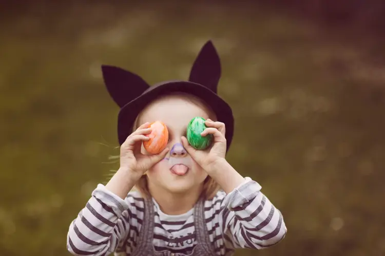 Jente som holder to påskeegg foran øyene og geiper