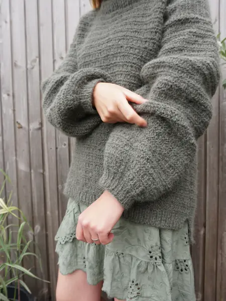 Dame med skjørt og grønn strikkegenser