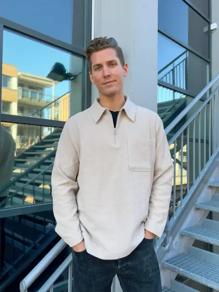 Menn med beige genser som smiler