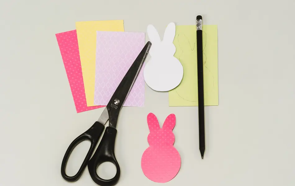 Fire forskjellige ark, to utklippede påskeharer, en saks og en penn