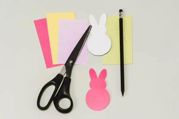 Fire forskjellige ark, to utklippede påskeharer, en saks og en penn