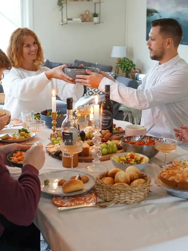 Dekket bord med mat og folk som smiler og deler mat