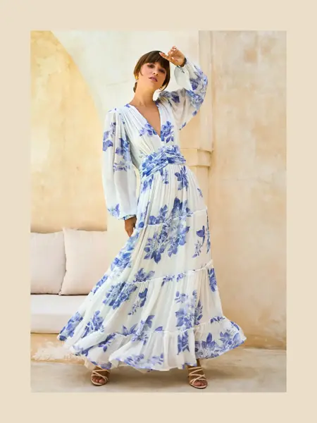 Dame med lang hvit og blåblomstrete kjole med lange ermer,