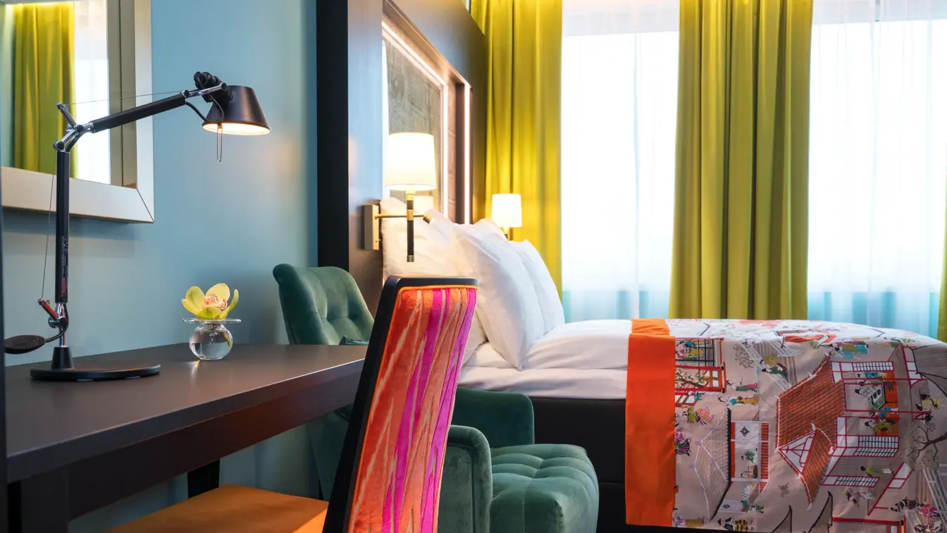 Dobbeltseng og arbeidspult med orange og rosa farger og orkide på pulten på standard double room på Hotel Stavanger midt i Stavanger sentrum