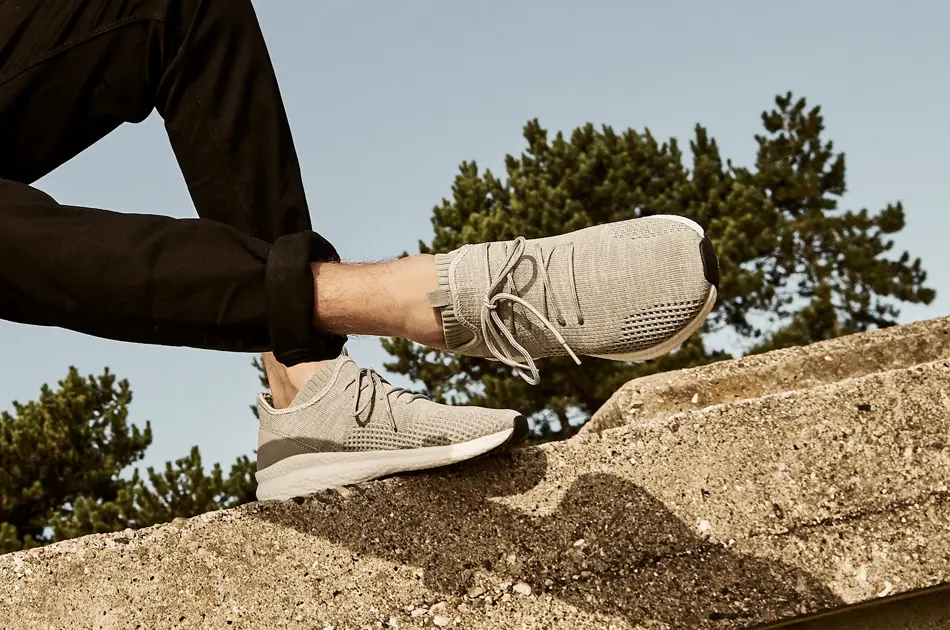 Grå herrejoggesko, med skog og blå himmel i bakgrunn.