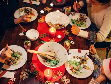 Folk som spiser vegetar julemiddag rundt et bord med rød duk