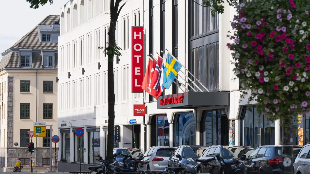 Fasaden til Thon Hotel Norge,  sett litt fra siden. Diverse flagg henger over inngangen.