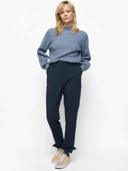 kvinnelig modell iført blå oversized genser og dressbukse