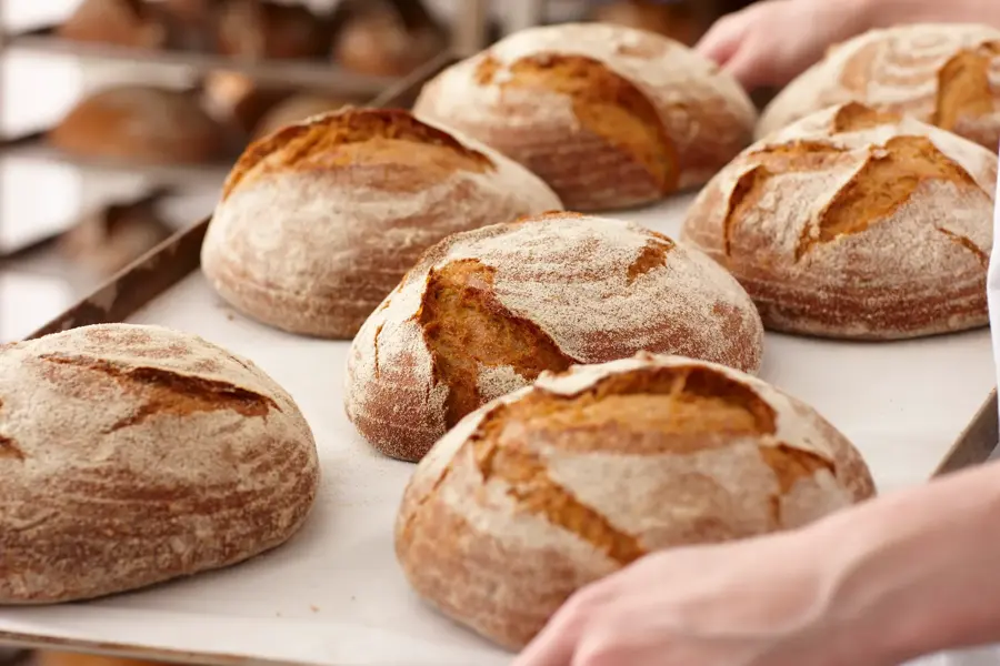 Brett med nystekt, rundt brød blir bært