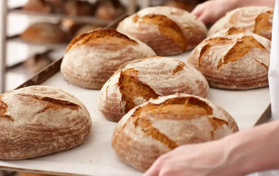 Brett med nystekt, rundt brød blir bært