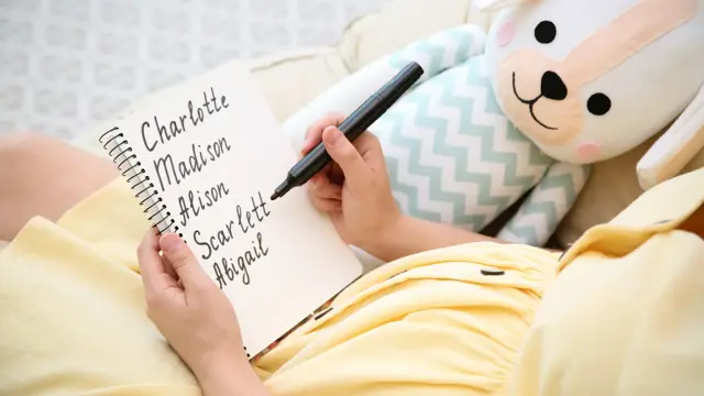 Pregnant woman with baby names list sitting in armchair, closeup