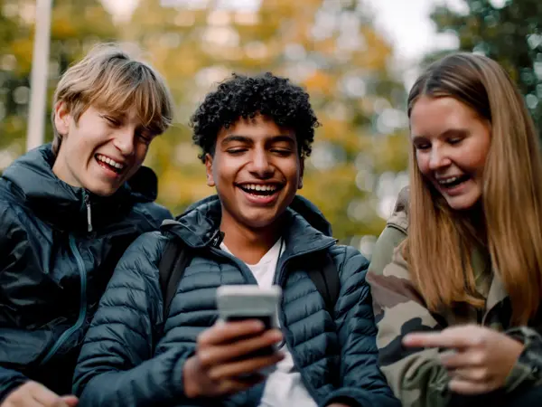ungdommer som ser på telefon påkledd allværsjakke
