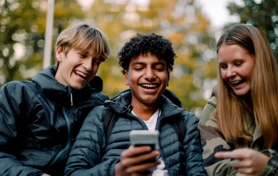 ungdommer som ser på telefon påkledd allværsjakke