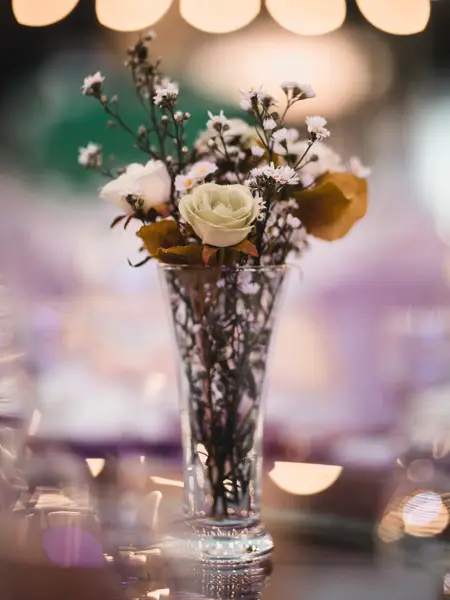 Blomsterbukett i vase med lys i bakgrunnen