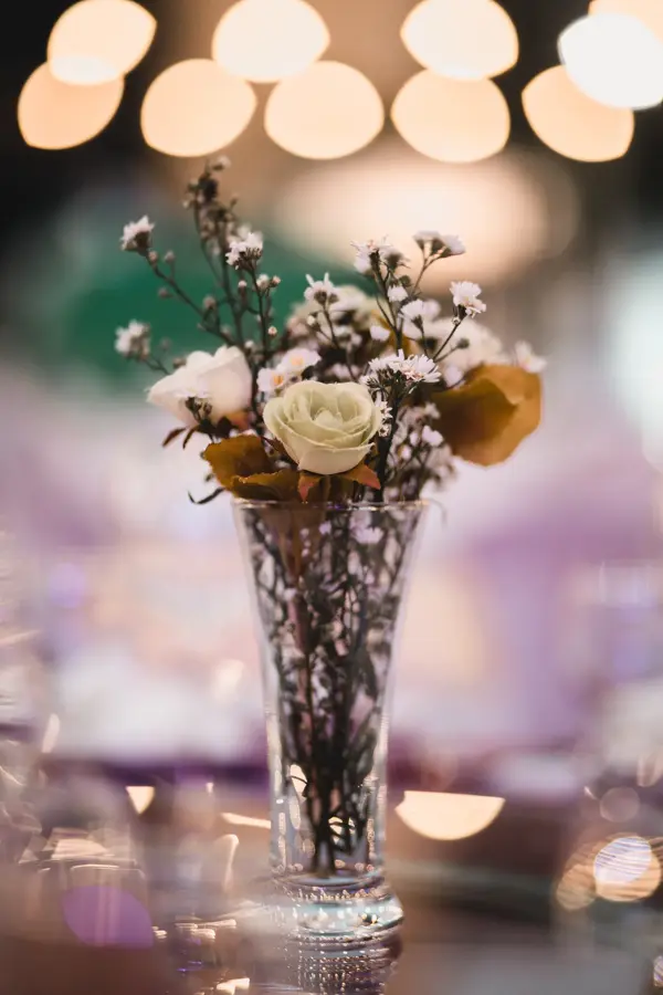 Blomsterbukett i vase med lys i bakgrunnen