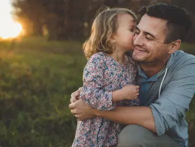 Jente kysser pappa på kinnet