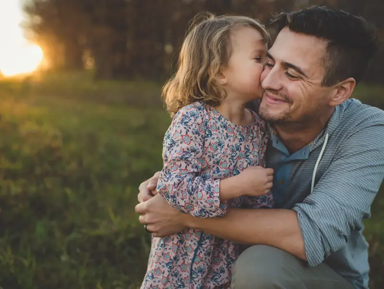Jente kysser pappa på kinnet