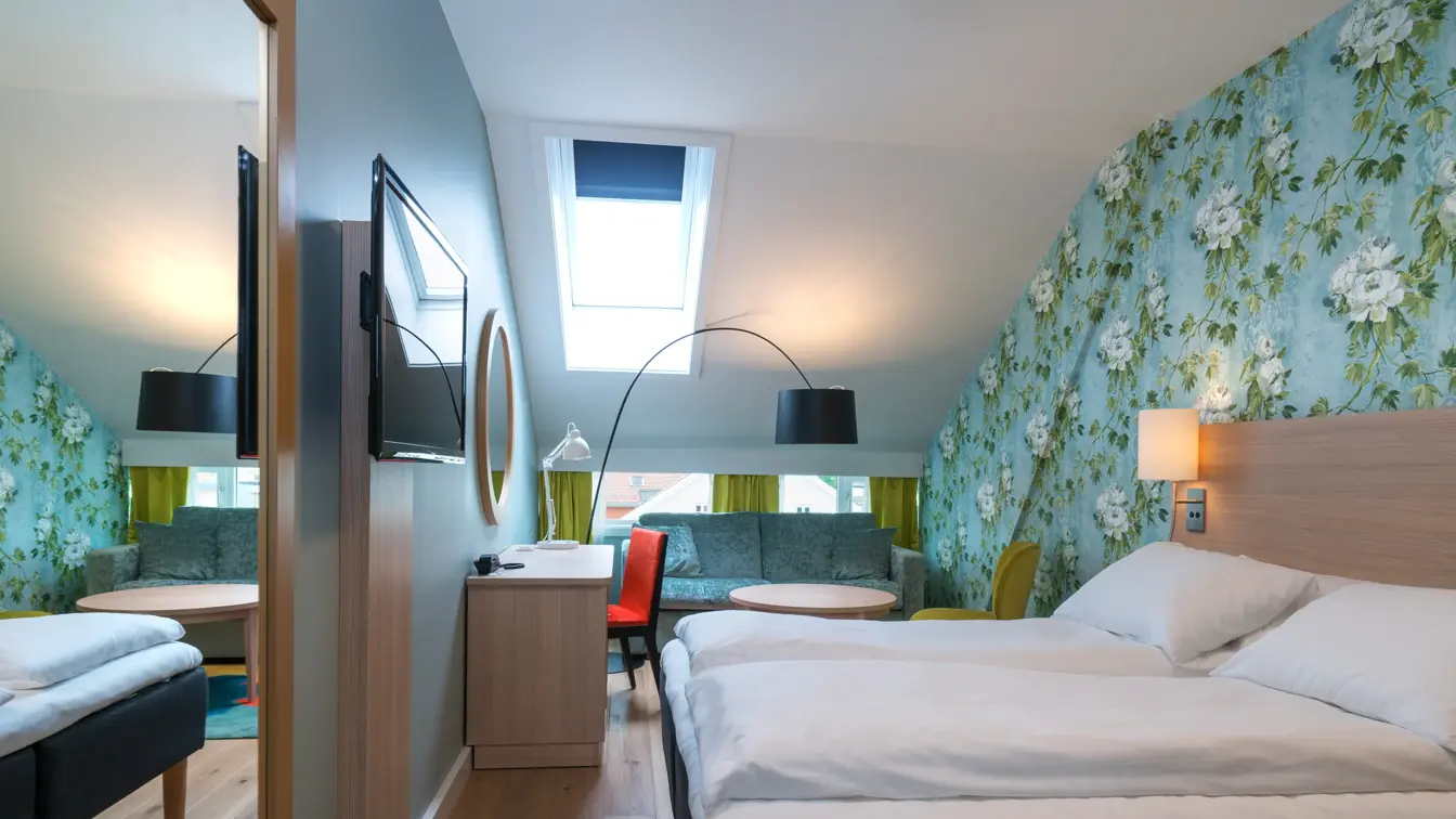Seng, TV, skrivebord, stol og sofagruppe i superiorrom på Thon Hotel Tønsberg Brygge