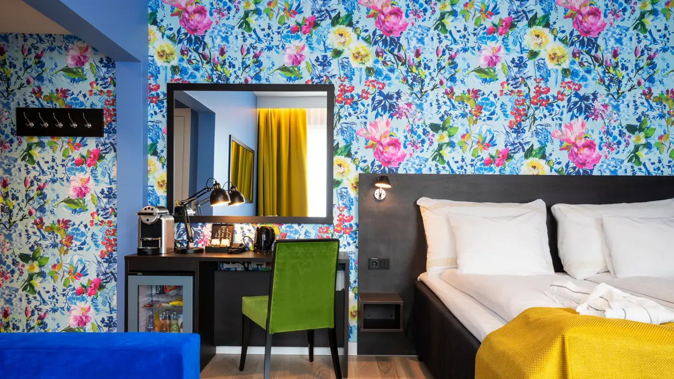 Skrivebord, speil, seng og blomstrete tapet  i business rom på Thon Hotel Moldefjord