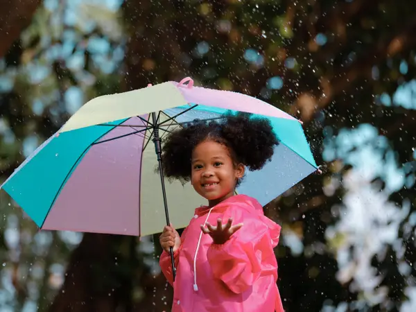 en jente som holder paraply og kledd i regnklær