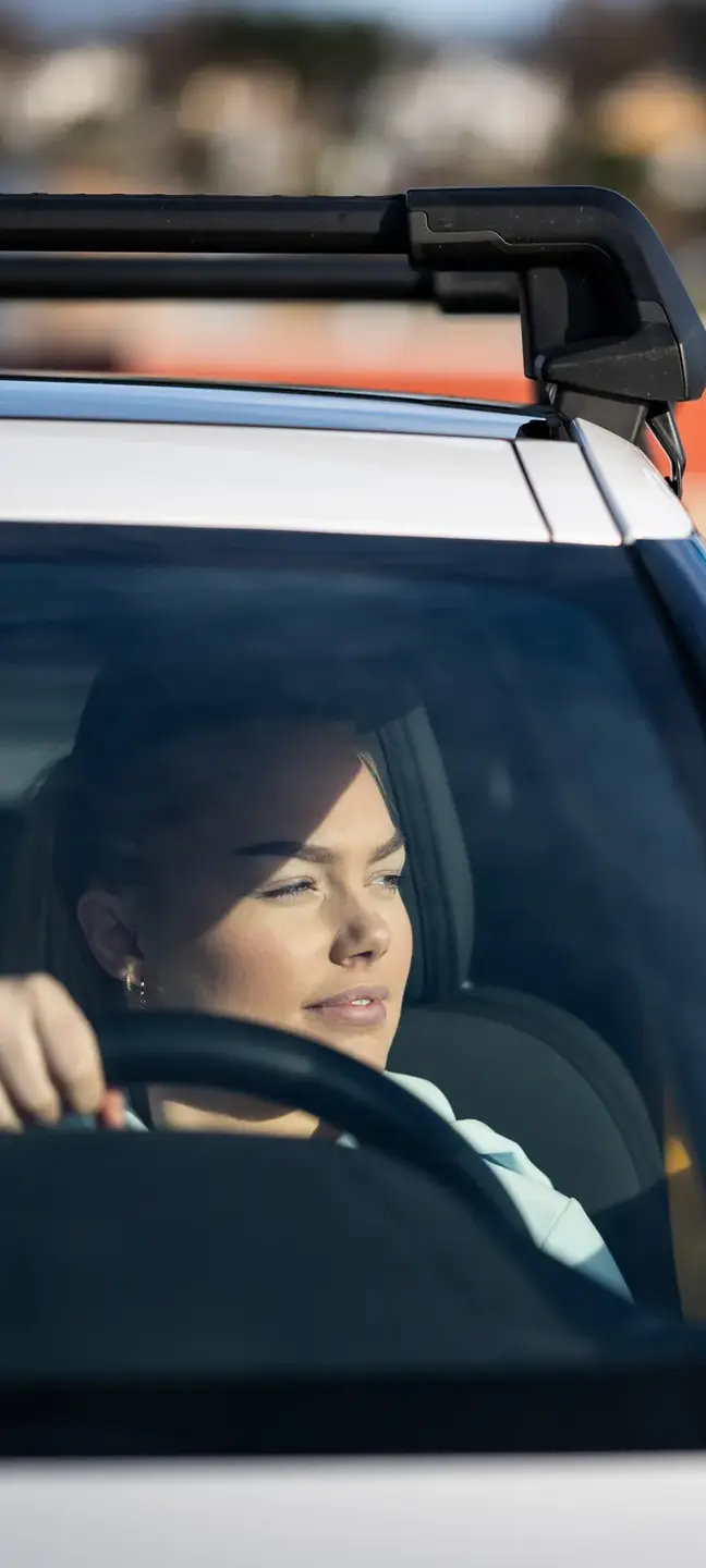En dame som sitter i bilen og ser ut av vinduet 