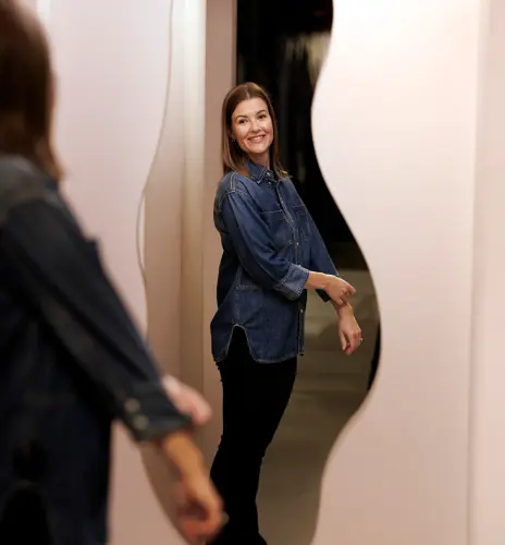 En kvinne står og ser på seg selv i et speil i et prøverom