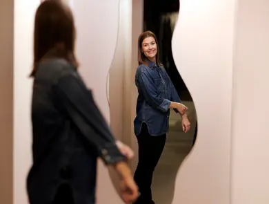 En kvinne står og ser på seg selv i et speil i et prøverom