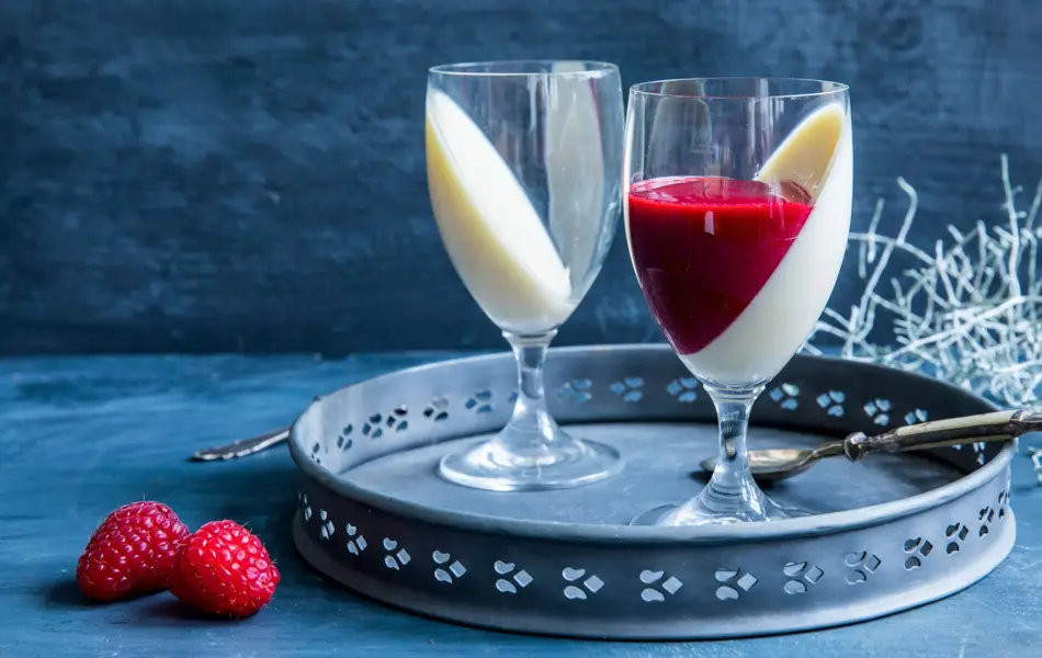 Et fat med to glass fylt med pannacotta og rød saus