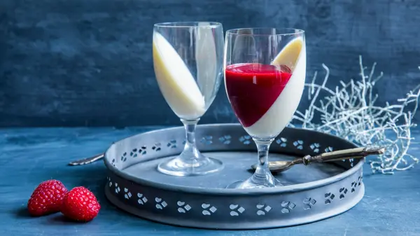 Et fat med to glass fylt med pannacotta og rød saus