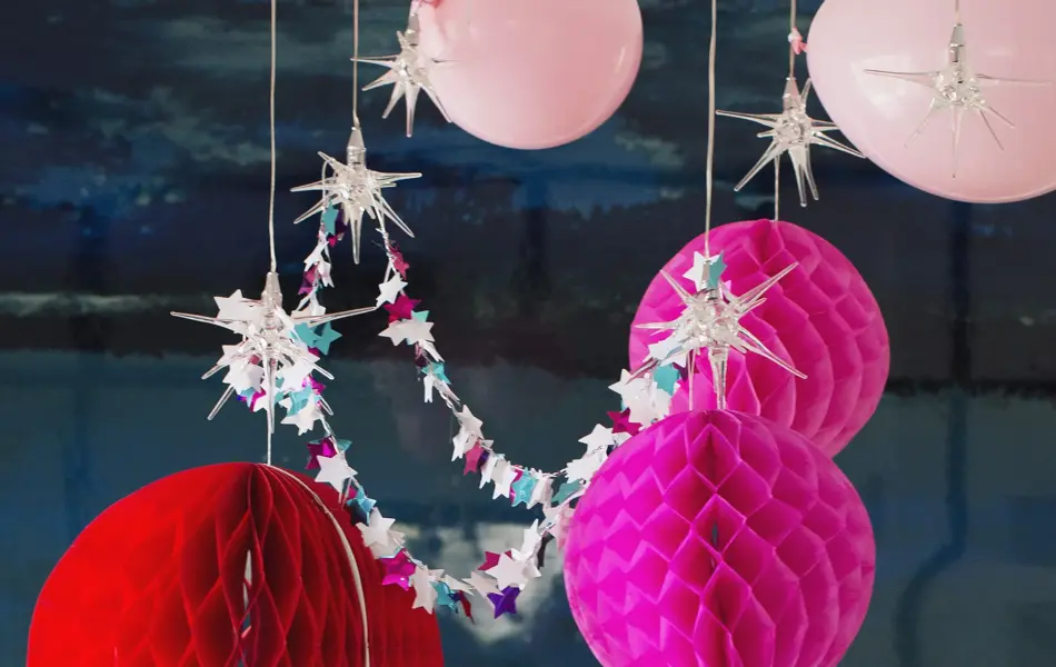 Røde og rosa ballonger, pom-poms og girlander henger i taket