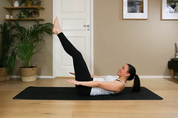 Anna viser Pilates-øvelser på treningsmatte på gulvet