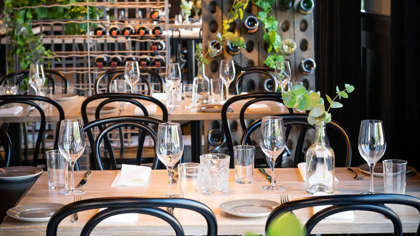 Dekket bord med grønne planter og industrilamper på Torvet Bistro på Thon Hotel Parken i Kristiansand sentrum