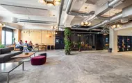 Interiør fra kontoret til The Oslo Company, stor og åpen sosial sone med rustikke detaljer som betonggulv og ventilasjon, grønne planter og lyse farger på veggene