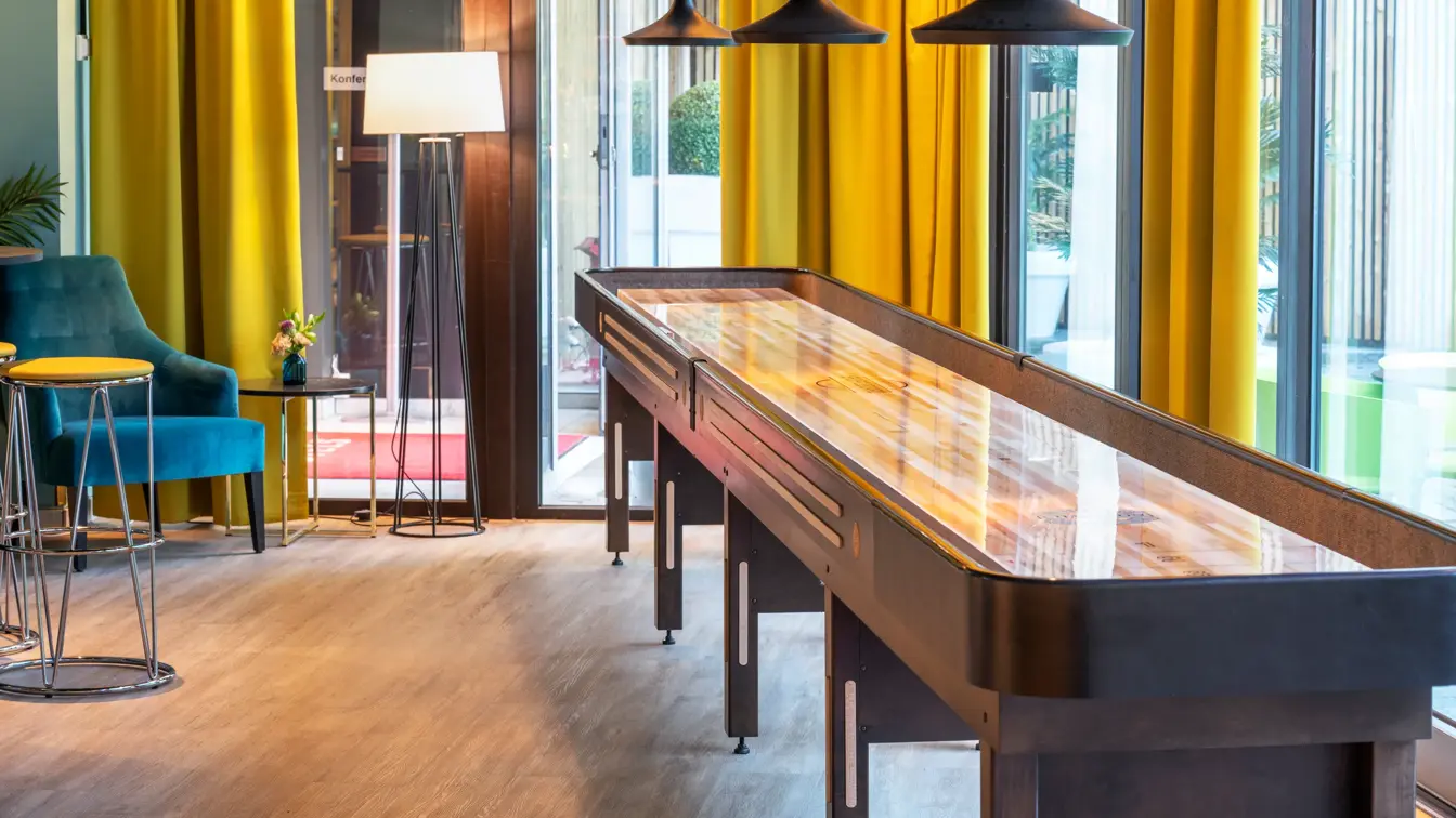 Shuffleboard, store vinduer og gule gardiner i lobbyen på Thon Hotel Maritim